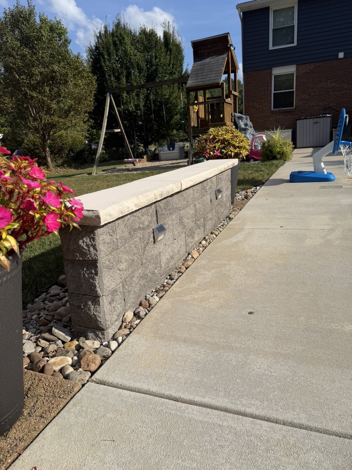 Stone seat wall with accent lighting along a pool deck